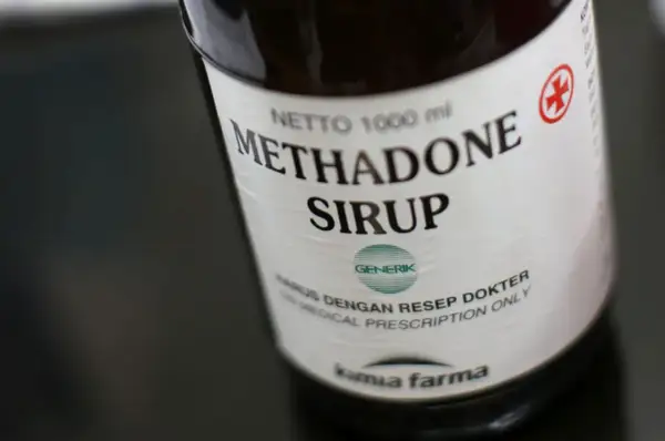 Butelka syropu metadonowego. Metadon co to? Lek wydawany na receptę, stosowany w leczeniu bólu i uzależnień.