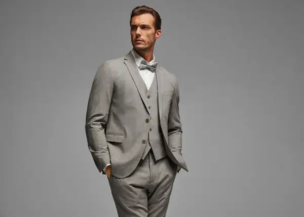 Ein Mann im eleganten grauen Anzug mit Weste und Fliege. So gelingt das Anzug reinigen ohne waschen.