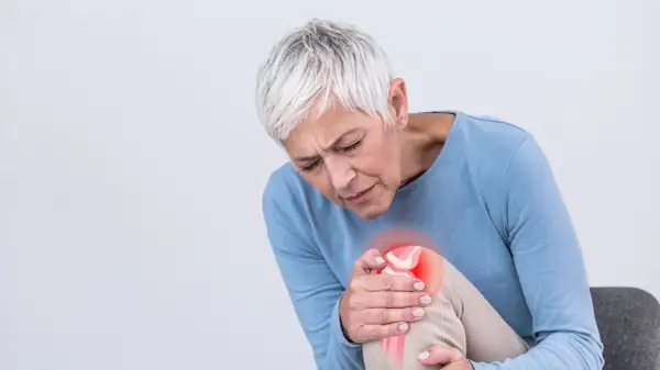 Frau mit Arthrose-Schmerzen im Knie, die sich fragt, welche Vitamine bei Arthrose helfen könnten.