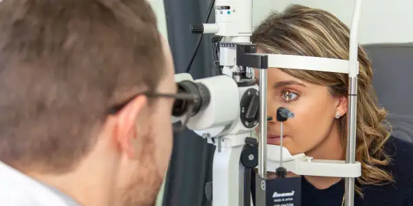 Un ophtalmologue examine l'œil d'une patiente avec un biomicroscope.