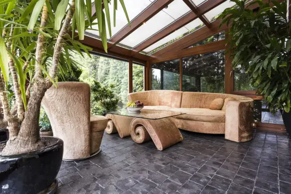 Gemütlicher Wintergarten mit üppiger Bepflanzung, bequemer Couch und einem einzigartigen Couchtisch. Tolle Ideen für Ihren Wintergarten!