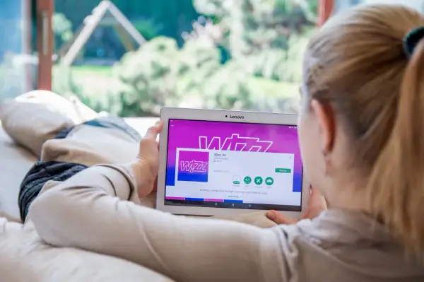 Kobieta przegląda w aplikacji Wizz Air na tablecie, planując tani lot.