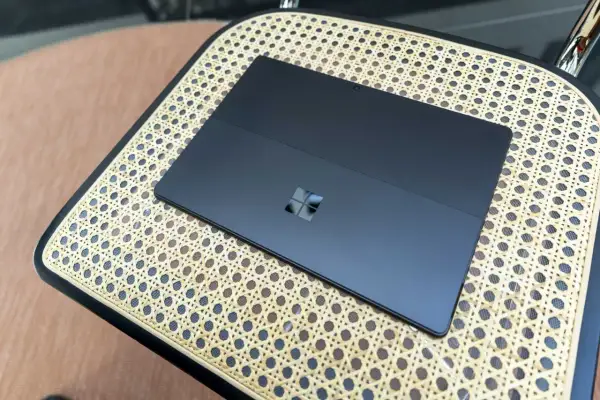 Ciemny tablet z logo Windows na plecach, działający na Windows 11 ARM, leży na plecionej powierzchni.