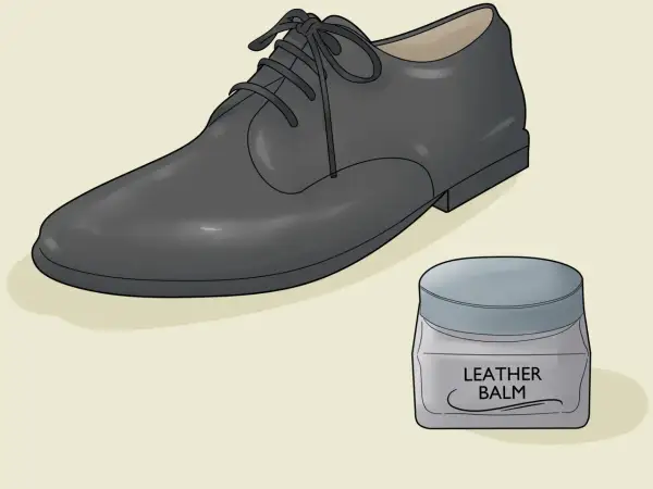 Un soulier en cuir noir et un pot de baume pour cuir. Apprenez comment assouplir des chaussures en cuir pour un confort optimal.