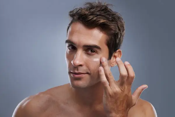 Hombre aplicándose crema en el rostro. El cuidado facial del hombre es esencial para una piel sana y radiante.