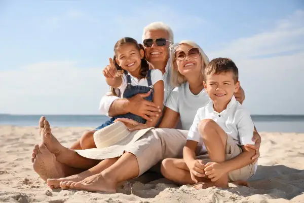 Famiglia felice in spiaggia, i nonni si godono il sole mentre i figli sono in vacanza con loro.