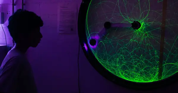 Ein Junge bestaunt ein Doppelpendel mit grünen Lichtspuren bei der Nacht der Wissenschaft Berlin.