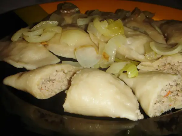 Pyszne pierogi z mięsem i kapustą, polane podsmażoną cebulką, kuszą swoim domowym wyglądem.