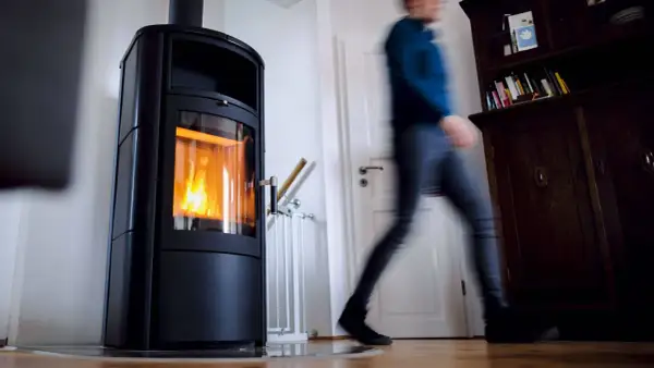 Ein Mann eilt an einer brennenden Holzheizung vorbei. Angesichts des möglichen Holzheizung Verbots 2030, wird diese Heizform bald Geschichte sein.