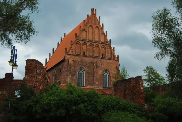Gotycka ceglana bazylika w **starym mieście Elbląg** z charakterystycznym szczytem i dachówką.