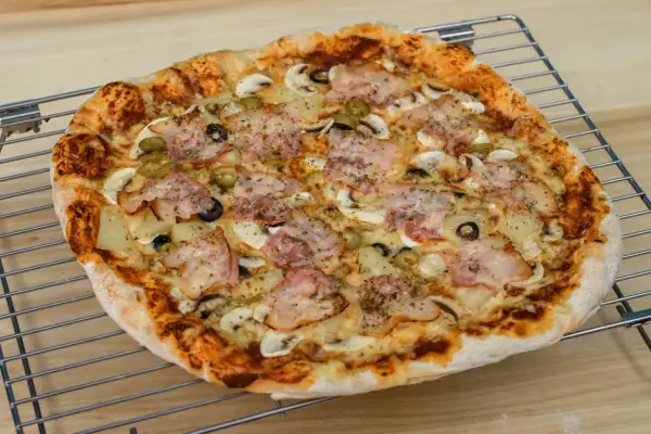 Pyszna pizza z szynką, pieczarkami, oliwkami i ananasem. Idealna na rodzinny obiad, zastanawiasz się ile piec pizze?