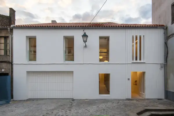 Fachada moderna con pintura al pliolite, puerta de garaje, ventanas y entrada iluminada.
