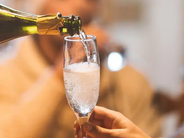 Ein Glas wird mit sprudelndem Cremant gefüllt. Was ist ein Cremant? Ein feiner Schaumwein, perfekt für besondere Anlässe.