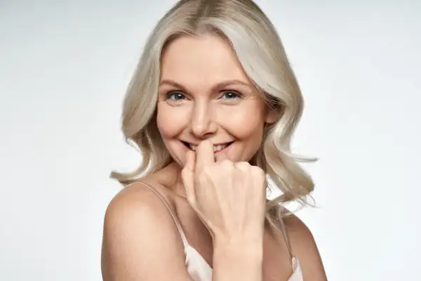 Uśmiechnięta kobieta z blond włosami, która lekko przygryza palec. Czy to fiksacja?
