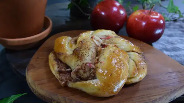 En gyllene kanelbulle med äppelbitar, redo att avnjutas.