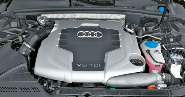 Silnik V6 TDI Audi z widocznym logo i oznaczeniem pojemności. Pod maską widać elementy układu dolotowego i płyny eksploatacyjne.