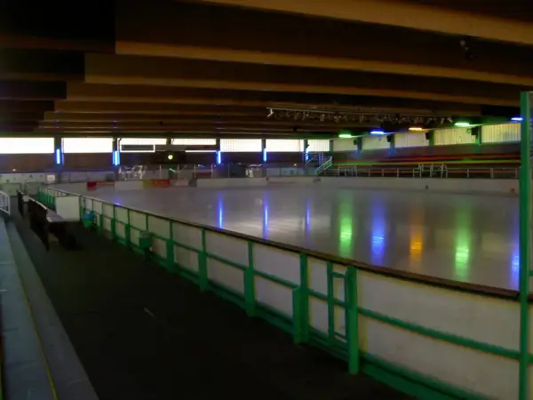 Leere Eisfläche in der Eissporthalle Bergisch Gladbach, beleuchtet von bunten Lichtern.