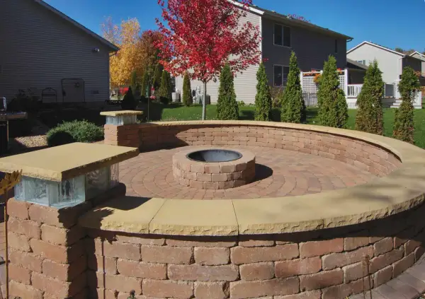 A circular brick patio features an in-ground fire pit, perfect for cozy evenings.