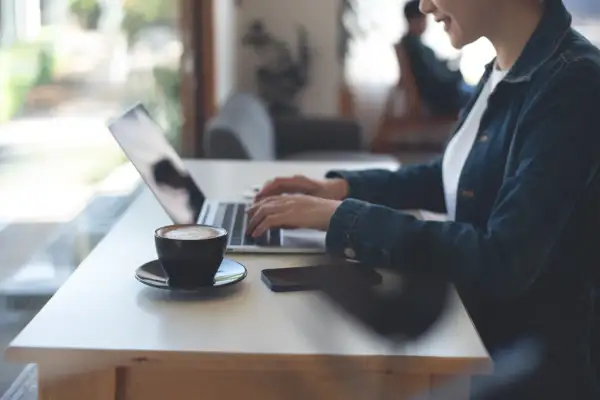 Kobieta pracuje zdalnie przy laptopie, popijając kawę. Nowy kodeks pracy reguluje takie formy zatrudnienia.