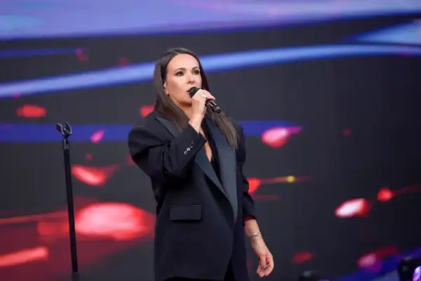 Kasia Kowalska w czarnej marynarce śpiewa na scenie, wykonując swoje utwory.