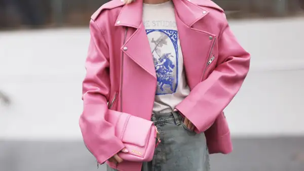 Giacca rosa in ecopelle, che dimostra il suo significato di alternativa sostenibile alla pelle animale. Borsa coordinata e jeans.