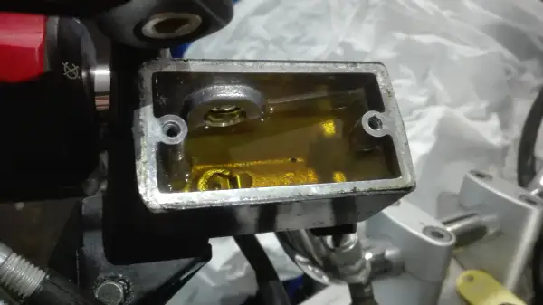 Zbiorniczek płynu hamulcowego w motocyklu z żółtym płynem.