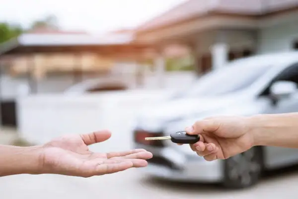 Une main tend une clé de voiture à une autre main ouverte. Idéal pour une assurance conducteur occasionnel.