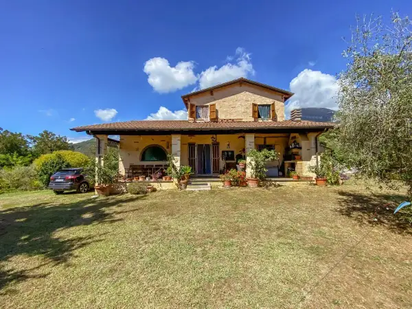 Una casa di campagna con un'auto parcheggiata, piante in vaso e un prato verde. Il momento perfetto quando comprare casa.