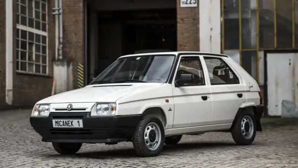 Biały Skoda Favorit z lat 90. na tle ceglanego budynku.