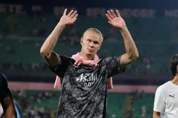 Erling Haaland z podniesionymi rękami, w koszulce z logo Asahi. Fani zastanawiają się nad jego datami dołączenia do drużyny.