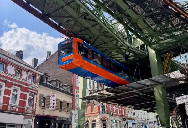 Die orange-blaue Schwebebahn fährt über den Dächern von Wuppertal.