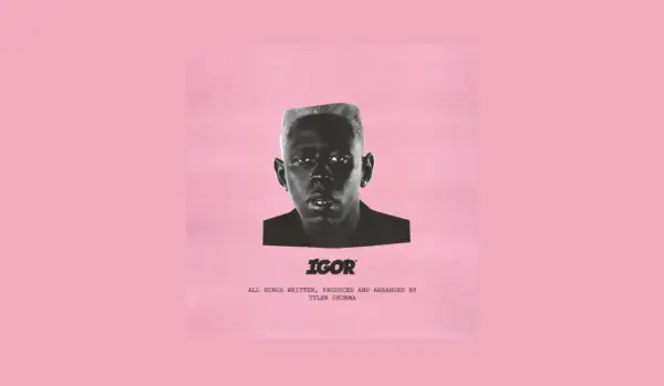 Okładka albumu "IGOR" Tylera, The Creatora. Czarno-białe zdjęcie artysty na różowym tle.