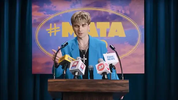Mata w niebieskiej marynarce przemawia za mównicą z mikrofonami, na tle napisu "#MATA".