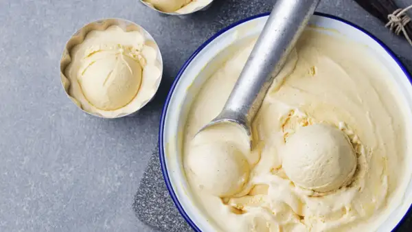 Krämig vaniljglass, perfekt för ett enkelt gelato recept. En skopa glass i en form och en stor skål med glass och skopa.