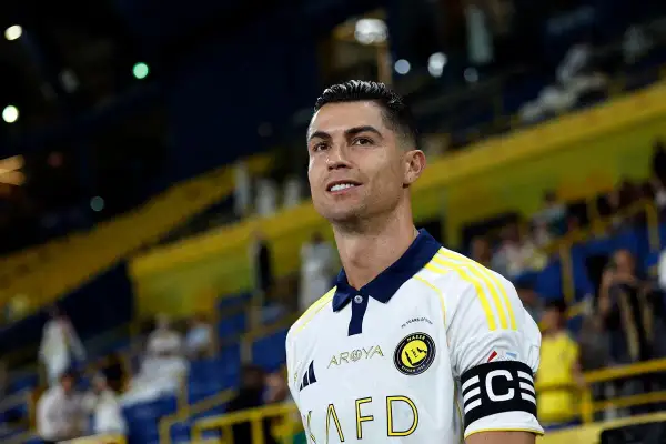 Cristiano Ronaldo w białej koszulce z żółtymi pasami, gotowy do gry. Na ramieniu opaska kapitana.