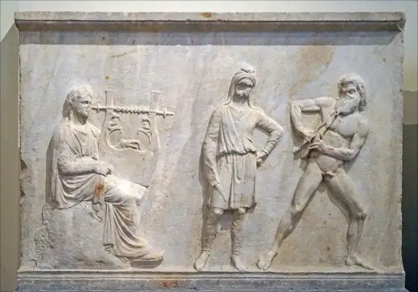 Bas-relief antique : une femme joue de la lyre, un homme au centre, et un homme nu jouant de la cithare, symbole Apollon.