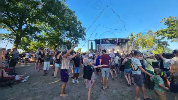 Seifenblasen schweben über einer fröhlichen Menge beim weinturm open air. Kinder und Erwachsene genießen die sommerliche Atmosphäre vor der Bühne.