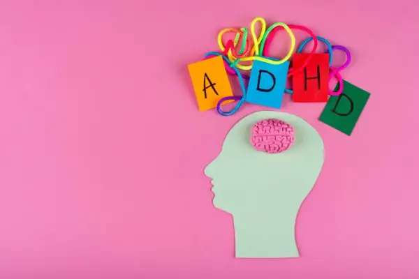 Sagoma di testa con cervello rosa e lettere colorate che formano ADHD, per capire come diagnosticarla.