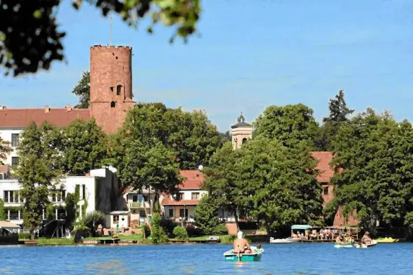 Widok na zamek i jezioro w jednym z malowniczych miast w lubuskim. Ludzie relaksują się na łodziach.