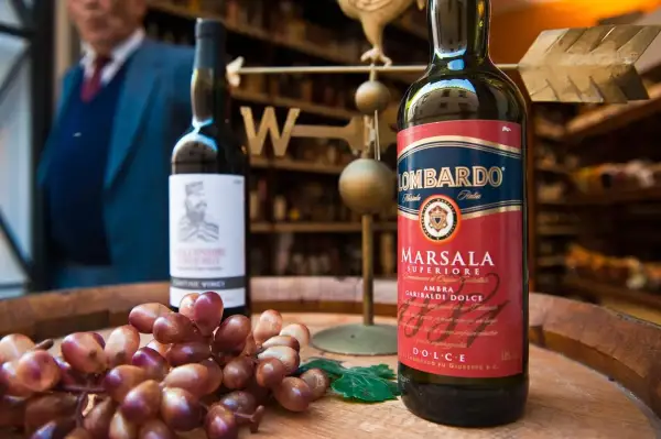 Słodkie wino deserowe Marsala Lombardo, obok kiść winogron.