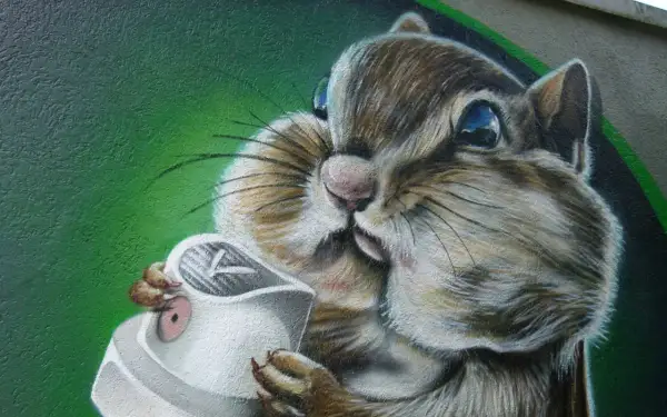 Graffiti eines Eichhörnchens, das eine Spraydose hält, vor grünem Hintergrund.