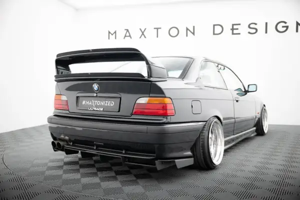 Czarne BMW E36 z tuningowym zderzakiem, dyfuzorem i dużym spoilerem.