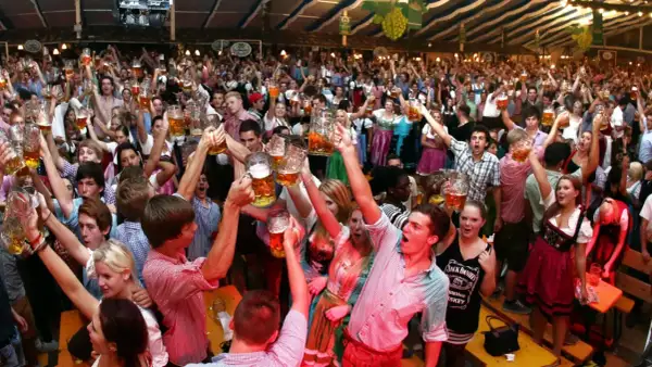 Menschen jubeln und stoßen mit Bierkrügen an auf dem Volksfest Freising.