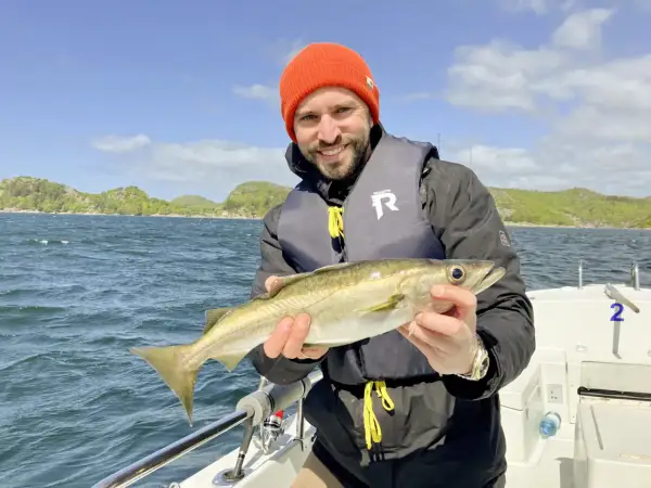 Glücklicher Angler mit frisch gefangenem Fisch vor der Küste von Farsund. Ein perfekter Tag für Angeln Hotspots!