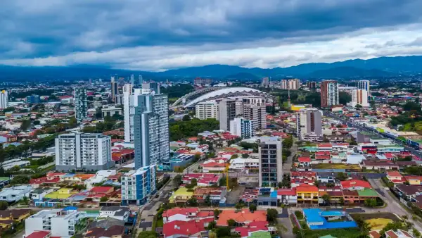 Vy över San José, Costa Rica, med moderna skyskrapor och färgglada hus under en molnig himmel.
