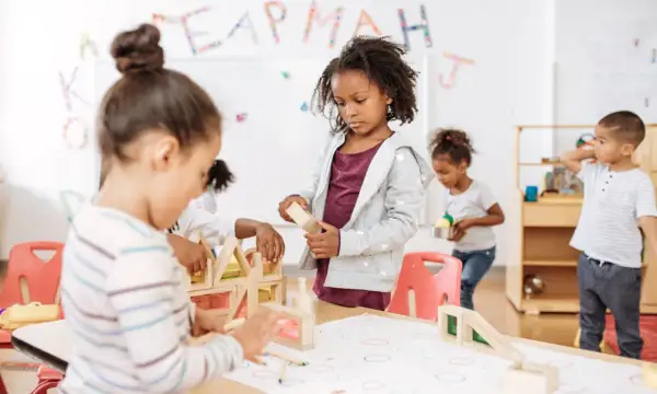 Kinderen bouwen met houten blokken, een typisch voorbeeld van freinet onderwijs waarbij leren door doen centraal staat.