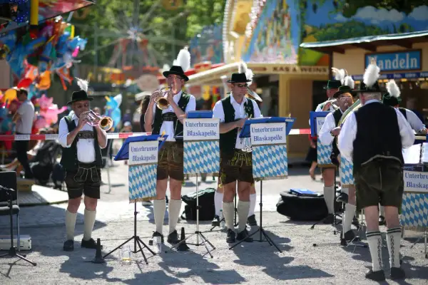 Blaskapelle spielt beim Taufkirchen Volksfest. Musiker in Tracht mit Hüten und Federn spielen Trompeten und Hörner.