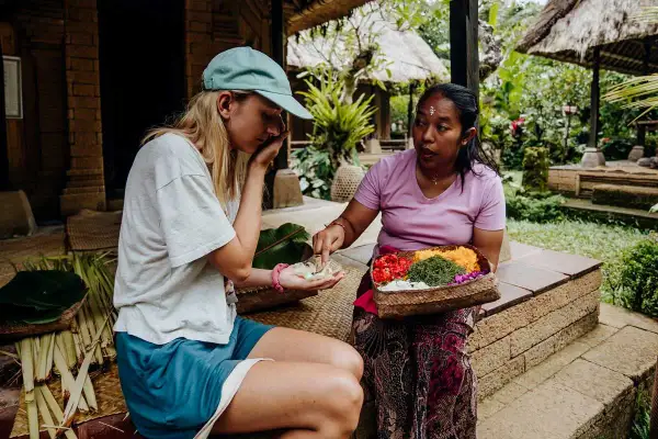 Une touriste apprend à faire des offrandes avec sa guide à Bali.