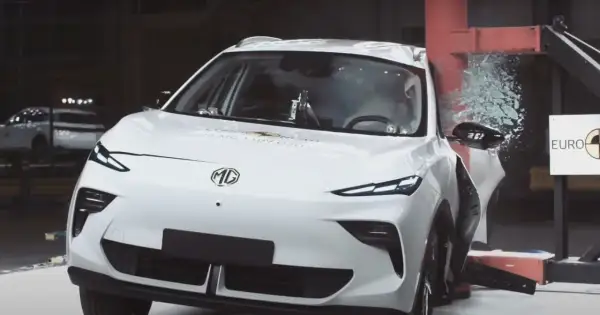Białe chinskie auto MG po teście zderzeniowym Euro NCAP, z rozbitą szybą i uszkodzonymi elementami.