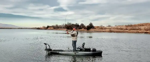 Pescatore su kayak con motore elettrico. Ottimo consiglio batteria motore elettrico per lunghe battute di pesca.